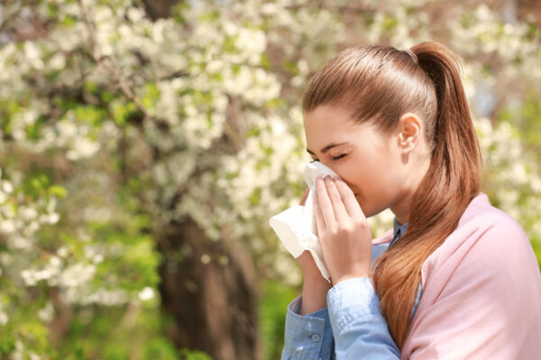 Sneezing,Young,Girl,With,Nose,Wiper,Among,Blooming,Trees,In